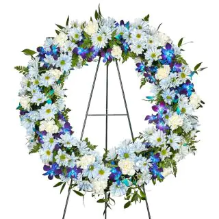 Wreath of white roses, carnations, daisies with blue orchids 
