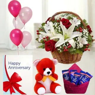 Basket of 2 white lilies, with 10 red roses, 6 inch teddybear, set of 5 dairy milk chocolates, anniversary greeting card with 5 blown balloons