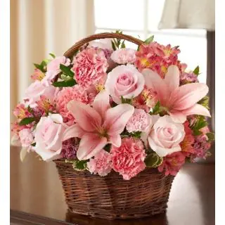 Arrangement of pink lilies with pink roes and pink carnations in cane basket