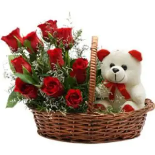 Basket Arrangement of 10 red roses with teddybear sitting in it 