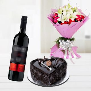 Bunch of red carnation with white lilies with heart shape chocolate truffle cake with bottle of red wine