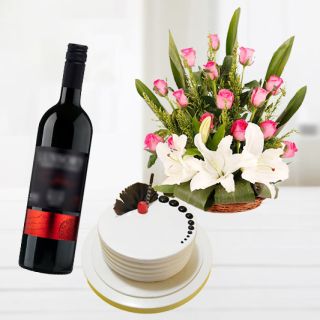 Basket of white lilies with pink roses with pineapple premium quality cake with bottle of red wine
