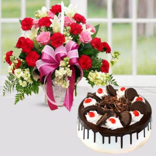 Basket arrangement of red and pink carnations with black forest cake 