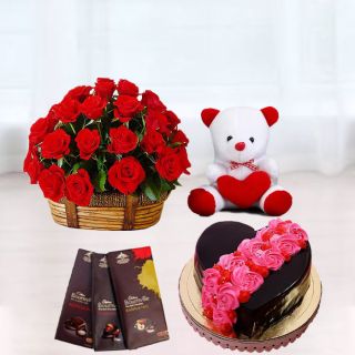 Basket of 15 red roses, heart shape chocolate cake with floral topping , set of 3 bournville chocolates, 6 inch white teddybear 