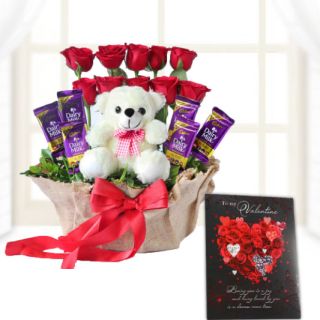 Beautiful arrangement of red roses, dairy milk chocolates, with teddy bear sitting in it with valentine day greeting card 