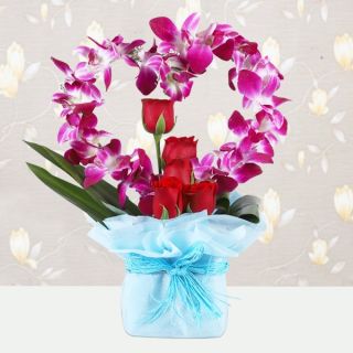 Beautiful vase arrangement of lavender orchids with red roses 