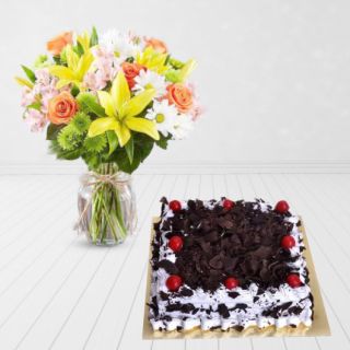 vase arrangement of lilies, roses and daisies, with black forest cake