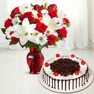 Vase arrangement of red carnations and white lilies with black forest cake 