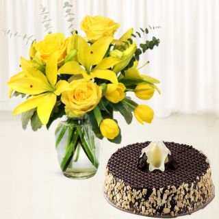 yellow lilies with yellow roses in glass vase with chocolate almond cake 
